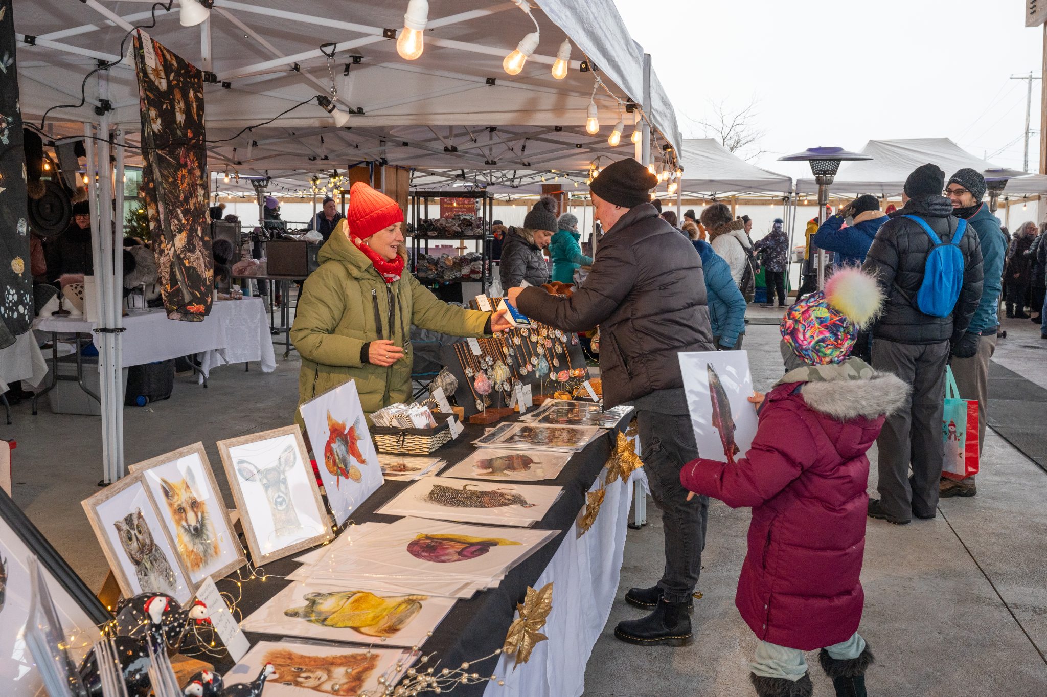 Exposants présentant ses produits artisanaux à des visiteurs lors du marché de Noël de Sainte-Adèle