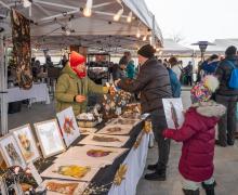 Exposants présentant ses produits artisanaux à des visiteurs lors du marché de Noël de Sainte-Adèle